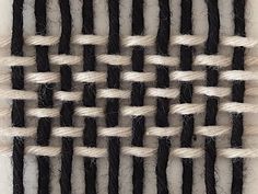 black and white woven material with rope on the bottom, in an abstract pattern that looks like weaving