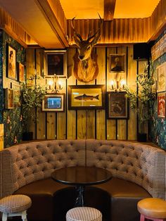 a corner booth with two stools and a deer head on the wall