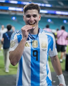 a young man is eating something with his mouth in the middle of a stadium field