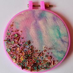 a pink and blue circular object with lots of beads on it's side, sitting on a white surface