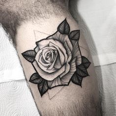 a black and white rose tattoo on the right side of the leg, with leaves around it