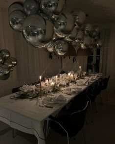 a long table is set with silver balloons and candles for an elegant dinner or party