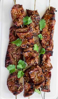 the skewers are covered with meat and garnished with cilantro