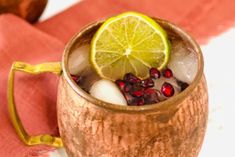 a cup filled with ice, lemon and pomegranate on top of a table