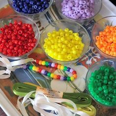 there are many different colored beads in the bowl on the tray with ribbons around them