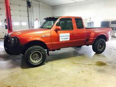 an orange pick up truck parked in a garage