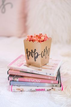 a bag full of popcorn sitting on top of some books in front of a bed