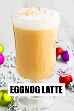 eggnog latte in a glass mug surrounded by christmas ornaments