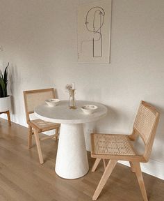 a white table and chairs in a room with wood flooring next to a plant