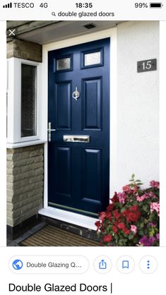 a blue front door on a house with flowers in the foreground and brick building behind it