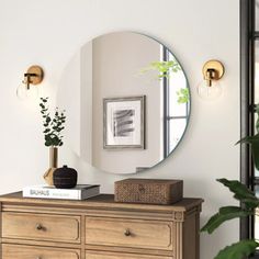 there is a mirror on the wall next to a dresser and potted plant in front of it