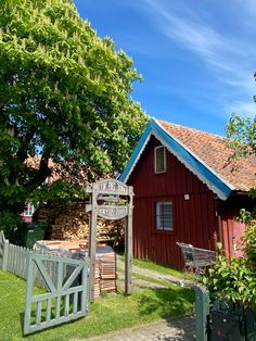 a small red house with a blue roof and white trim on the front, next to a wooden gate