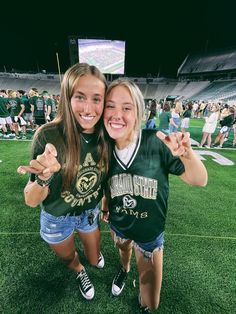 two girls posing for the camera at a football game