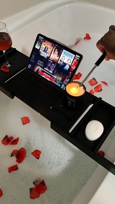 a cell phone sitting on top of a bath tub filled with water and rose petals