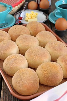 several rolls in a baking pan on a table with eggs, butter and other ingredients