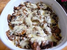 a white bowl filled with mushrooms covered in cheese