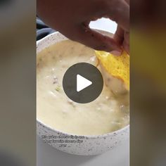 a person is dipping something into a bowl with a tortilla chip in it