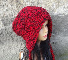 a mannequin head wearing a red and black knitted hat on top of a rock