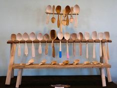 wooden spoons are lined up on a shelf in front of a wall mounted rack