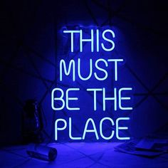 a neon sign that says, this must be the place in front of a computer