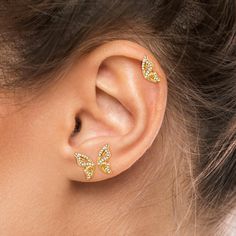 a close up of a person's ear with two small yellow butterflies on it