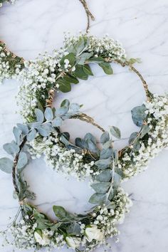 three wreaths with white flowers and greenery laid out on a marble countertop