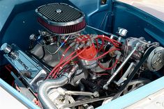 an engine in the back of a blue truck with red hoses on it's side