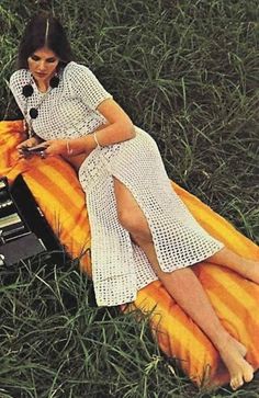 a woman laying in the grass next to an old radio