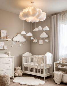 a baby's room with white furniture and clouds hanging from the ceiling over the crib