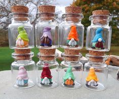 small glass jars with tiny figurines in them on top of a table outside