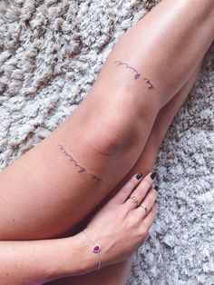 a woman's legs with small tattoos on them