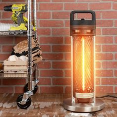 an electric heater sitting on top of a wooden table next to a brick wall