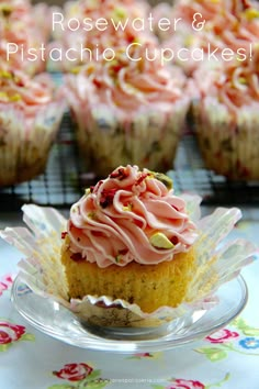 some cupcakes with pink frosting and sprinkles on top are sitting on a plate