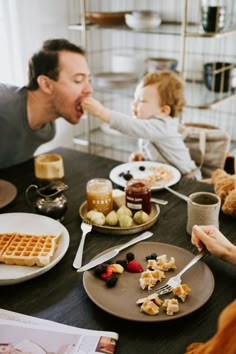 a man and child sitting at a table eating waffles