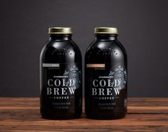 two bottles of cold brew coffee sitting on top of a wooden table next to each other