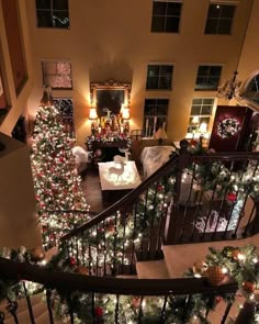 christmas trees are lit up on the stairs in this home's living room, which is decorated with lights and garlands