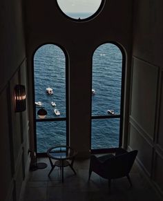 two large windows overlooking the water and boats in the ocean are seen from inside a house