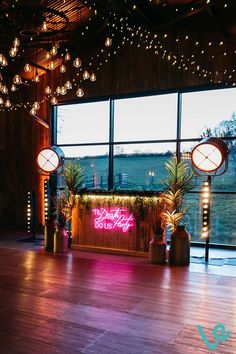 an empty dance floor with lights hanging from the ceiling and potted plants on either side