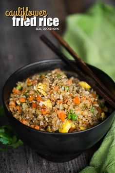 a black bowl filled with fried rice and vegetables