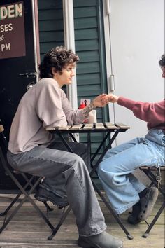 two people sitting at a table and one is holding the hand of another person's hand