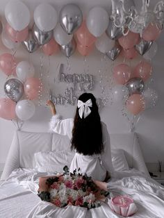 a woman sitting on top of a bed in front of balloons