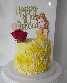 a birthday cake with yellow frosting and a red rose sitting on top of it