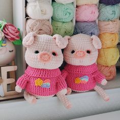 two crocheted pigs are sitting next to each other in front of yarn balls