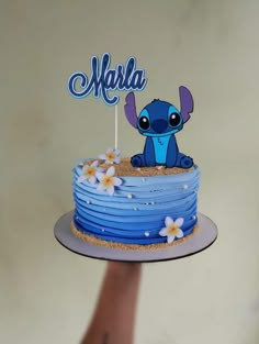 a hand holding a cake with a blue frosting that says marla on it