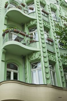 a tall green building with balconies and windows