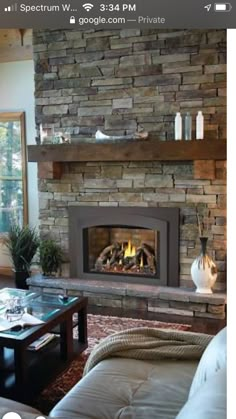 a living room filled with furniture and a fire place in the middle of a stone fireplace