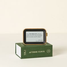 an electronic device sitting on top of a green book cover with the words author clock printed on it