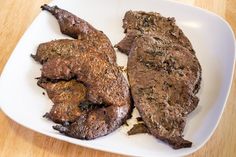 two pieces of steak on a white plate