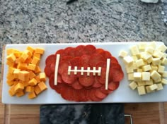 a football shaped platter with cheese, meat and veggies on the side