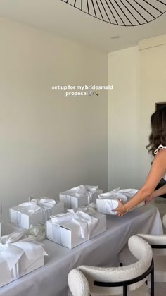 a woman standing over a table filled with white boxes